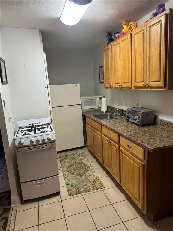 kitchen featuring white appliances, light tile patterned flooring, and sink