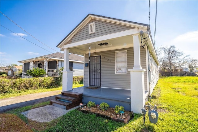 bungalow featuring covered porch and a front lawn