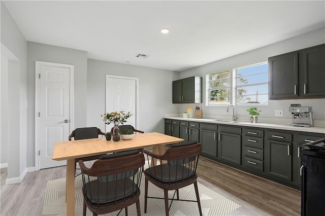 kitchen with black range with electric cooktop, light wood-type flooring, and sink