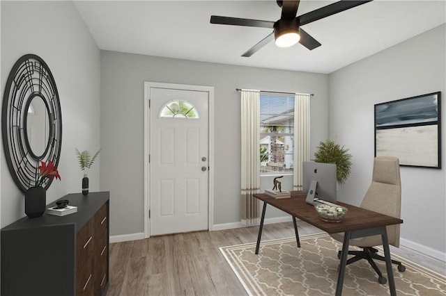 home office with light hardwood / wood-style floors and ceiling fan