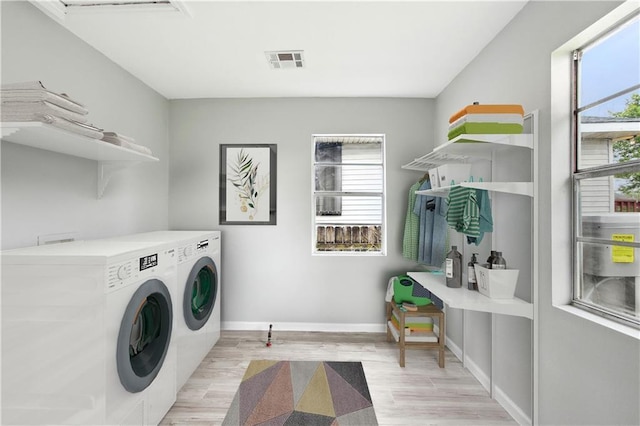 laundry room with light wood-type flooring, separate washer and dryer, and a wealth of natural light