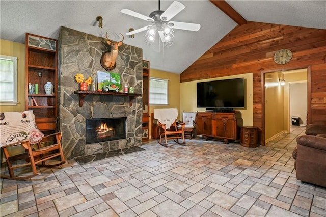 living room featuring ceiling fan, beamed ceiling, wooden walls, high vaulted ceiling, and a fireplace