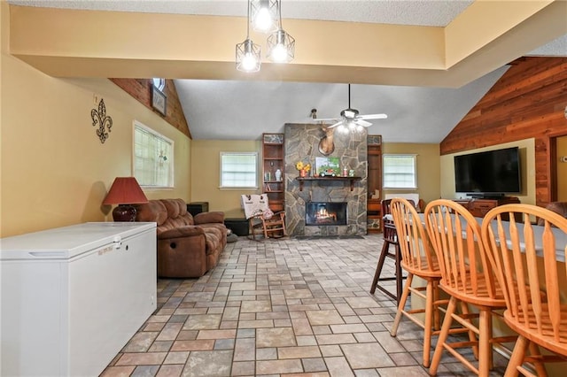 living room featuring ceiling fan, a fireplace, wood walls, and vaulted ceiling