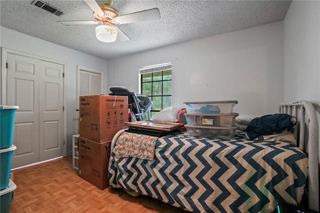 bedroom with a closet, ceiling fan, light parquet floors, and a textured ceiling