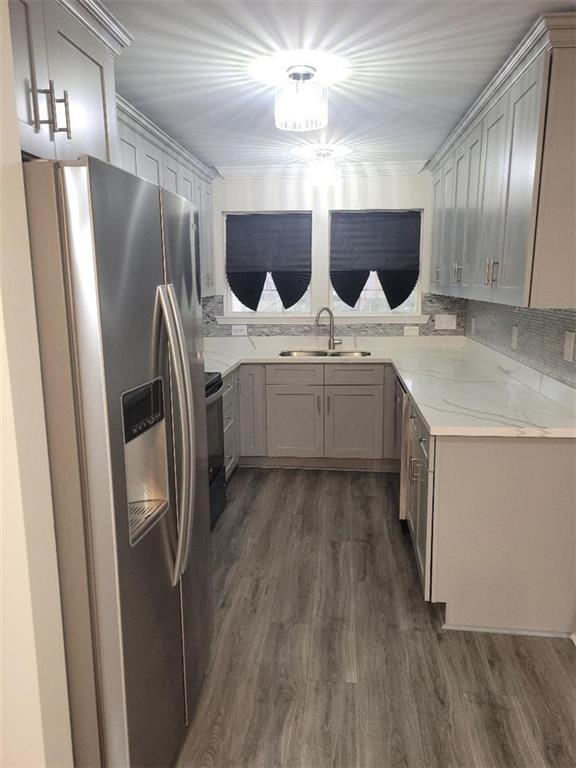 kitchen featuring light stone counters, stainless steel fridge, sink, gray cabinets, and dark hardwood / wood-style flooring