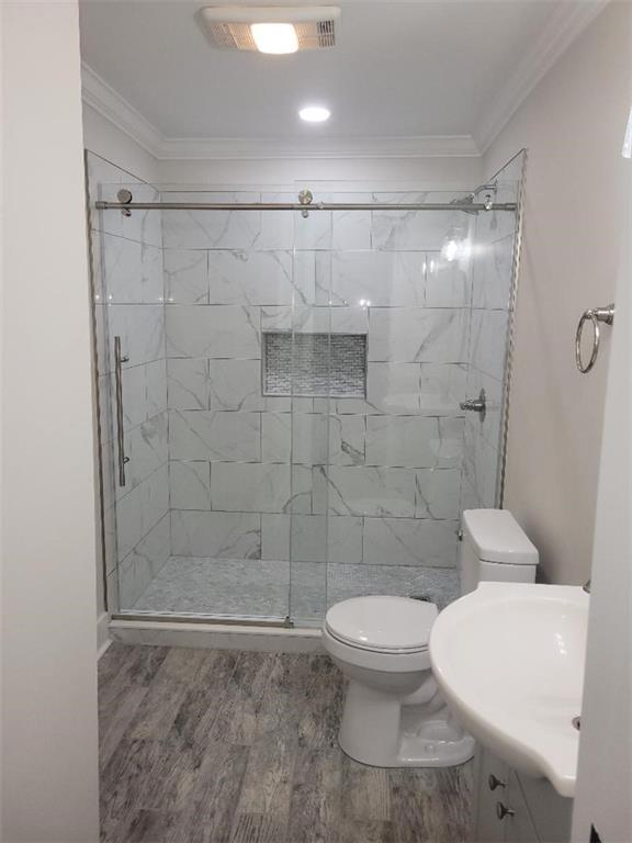 bathroom with vanity, an enclosed shower, hardwood / wood-style flooring, crown molding, and toilet