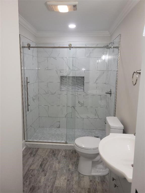 4985 Feliciana Dr, New Orleans, LA 70126 - full bathroom featuring a shower stall, wood finished floors, toilet, crown molding, and a sink
