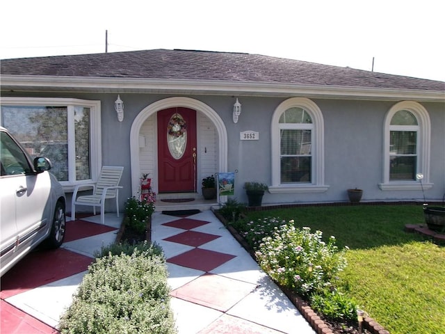 view of exterior entry featuring a lawn and a porch