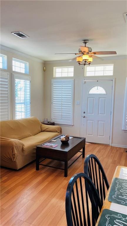 living room featuring light wood-type flooring, plenty of natural light, and ornamental molding