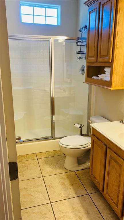 bathroom with vanity, a shower with shower door, toilet, and tile patterned floors