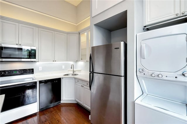 kitchen with stacked washer and dryer, sink, white cabinetry, appliances with stainless steel finishes, and dark hardwood / wood-style flooring