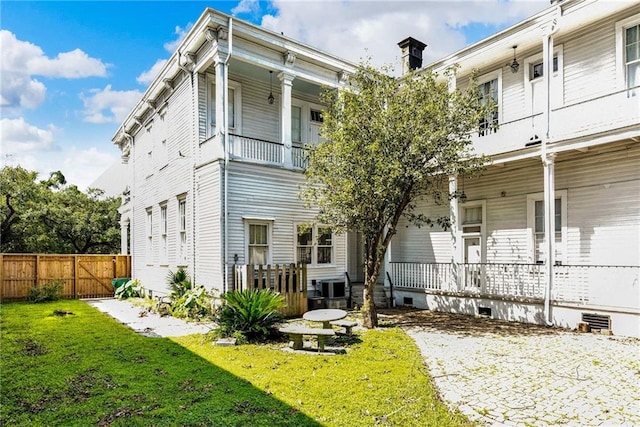 back of property with a balcony, a patio, and a yard