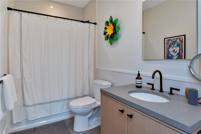 bathroom with tile walls, toilet, vanity, shower / tub combo with curtain, and tile patterned floors