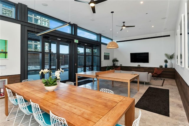 dining space featuring ceiling fan, a high ceiling, and a wall of windows