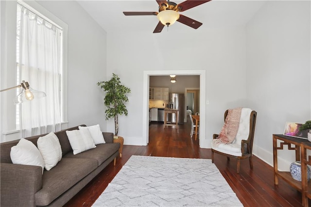 living room with a healthy amount of sunlight, ceiling fan, and dark wood-type flooring