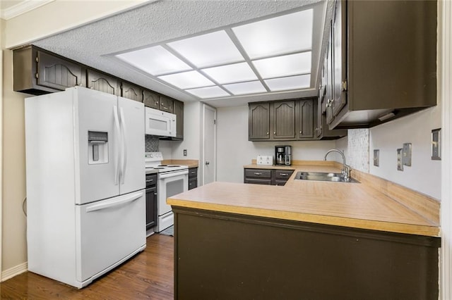 kitchen with dark hardwood / wood-style floors, sink, kitchen peninsula, white appliances, and dark brown cabinetry