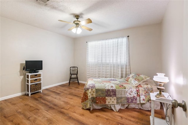 bedroom with wood-type flooring, ceiling fan, and a textured ceiling