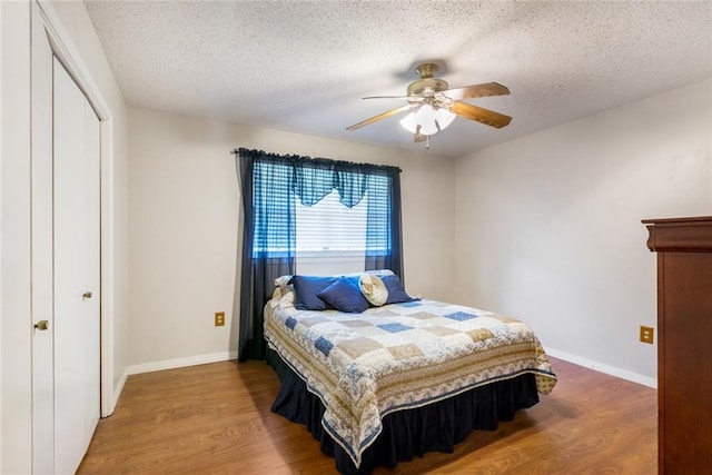 bedroom with a closet, ceiling fan, hardwood / wood-style flooring, and a textured ceiling