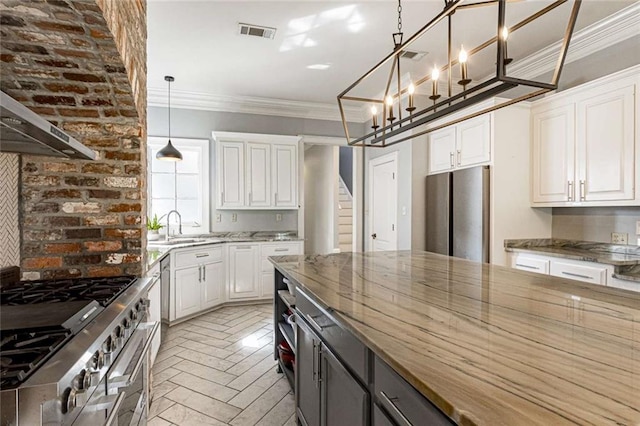 kitchen featuring hanging light fixtures, white cabinets, stainless steel appliances, crown molding, and sink