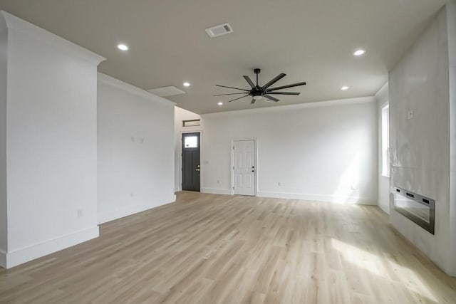 spare room featuring ceiling fan, heating unit, light hardwood / wood-style flooring, and a large fireplace