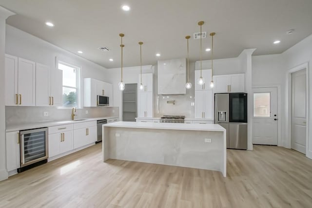 kitchen with beverage cooler, a center island, appliances with stainless steel finishes, and white cabinetry