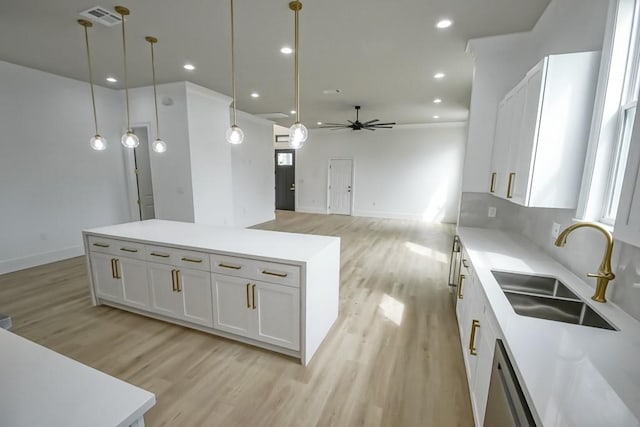 kitchen featuring white cabinets, a kitchen island, pendant lighting, ceiling fan, and sink