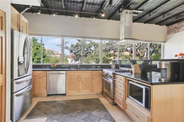 kitchen with light brown cabinets, sink, island range hood, rail lighting, and appliances with stainless steel finishes