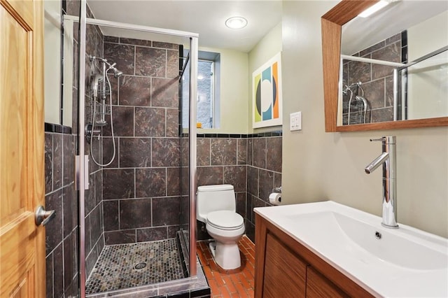 bathroom with tile walls, vanity, toilet, and an enclosed shower