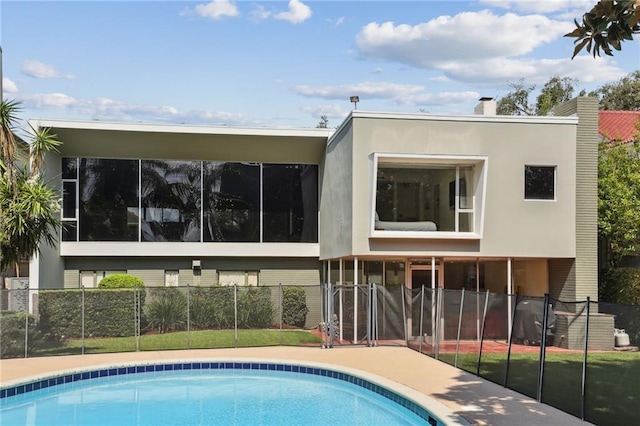 rear view of house featuring a sunroom and a fenced in pool