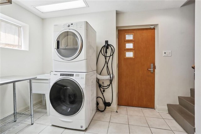 clothes washing area featuring stacked washer / drying machine and light tile patterned flooring