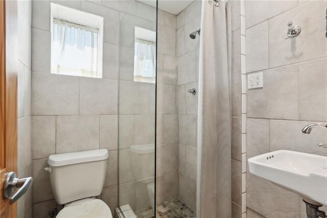 bathroom with a shower with shower curtain, tile walls, sink, and toilet