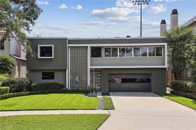 raised ranch featuring a garage and a front lawn