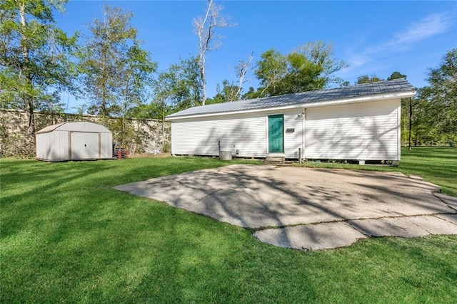 rear view of property featuring a storage shed, a yard, and a patio area