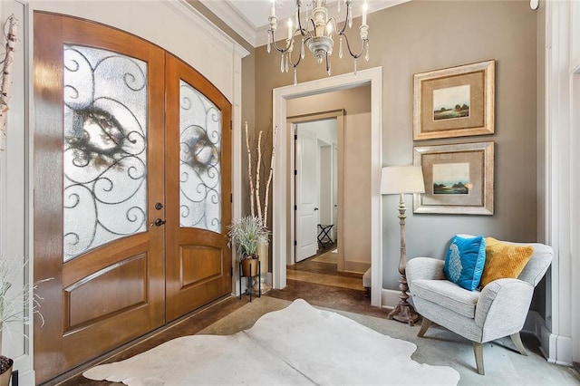 carpeted entryway featuring crown molding, a chandelier, and french doors