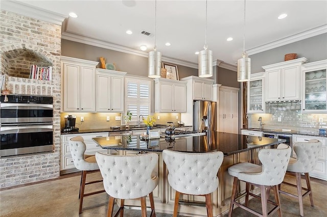 kitchen with hanging light fixtures, ornamental molding, tasteful backsplash, appliances with stainless steel finishes, and a center island