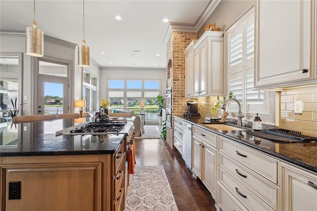 kitchen with dark stone counters, hanging light fixtures, sink, and a kitchen island