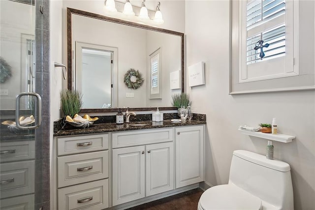 bathroom with walk in shower, vanity, and toilet