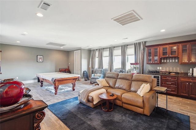 rec room with pool table, ornamental molding, light hardwood / wood-style flooring, and indoor bar