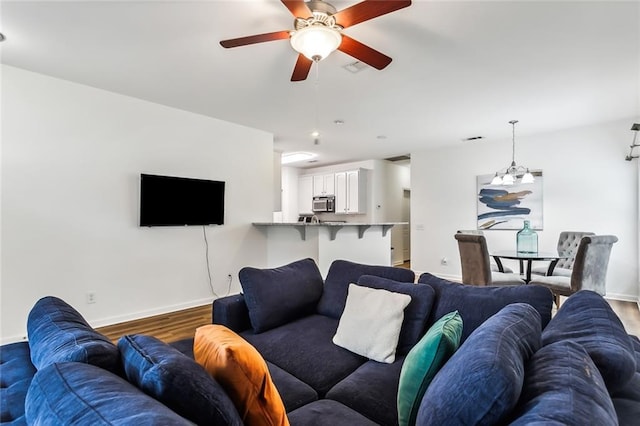 living room featuring wood-type flooring and ceiling fan with notable chandelier