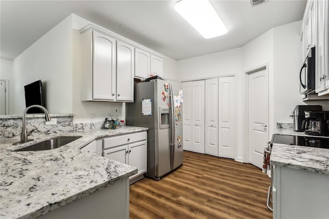 kitchen featuring light stone countertops, stainless steel fridge, dark wood-type flooring, sink, and white cabinetry