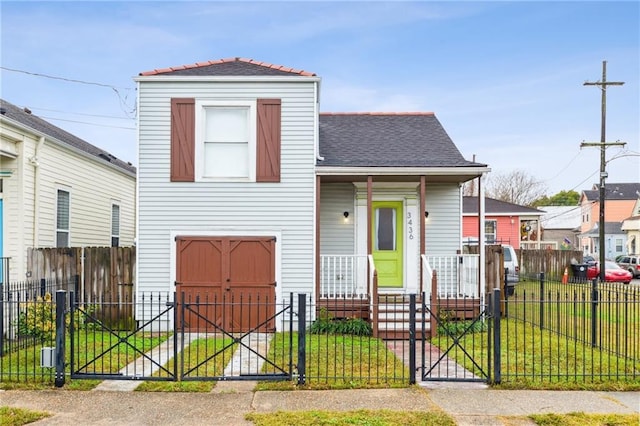 view of front of property featuring a porch, a fenced front yard, a gate, roof with shingles, and a front lawn