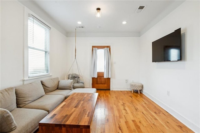 living room featuring visible vents, plenty of natural light, and light wood-style floors