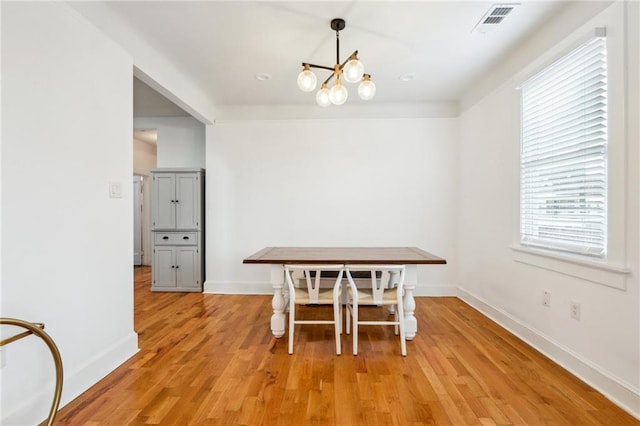 dining room with a chandelier, baseboards, visible vents, and light wood-style floors