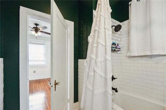 bathroom featuring baseboards, shower / tub combo, wood finished floors, and a ceiling fan