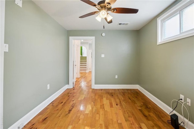 spare room with visible vents, light wood-type flooring, a ceiling fan, and baseboards