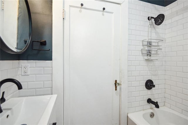 bathroom with tiled shower / bath combo, tile walls, and sink