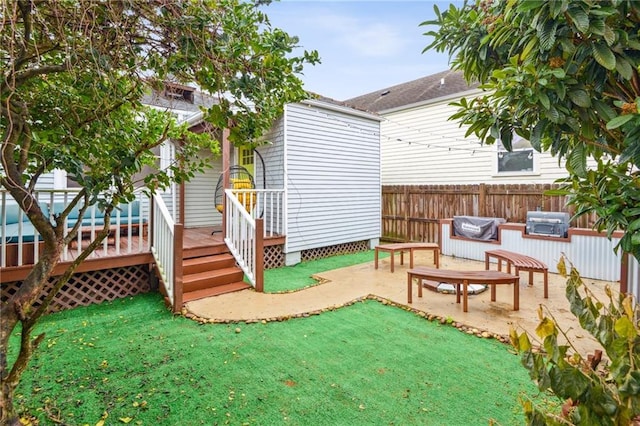 view of play area with a yard, a wooden deck, and a patio area