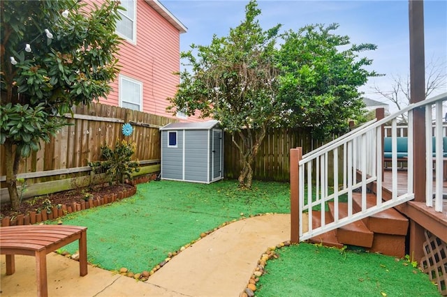 view of yard featuring an outdoor structure, a fenced backyard, a wooden deck, and a storage shed