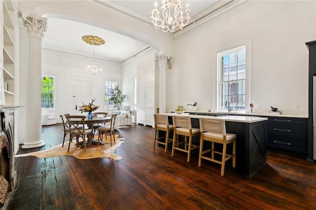 600 Esplanade Ave Unit 1, New Orleans, LA 70116 - dining area featuring decorative columns, ornamental molding, arched walkways, dark wood-style floors, and a notable chandelier