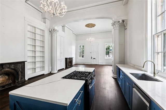 kitchen featuring appliances with stainless steel finishes, hanging light fixtures, blue cabinetry, an inviting chandelier, and sink